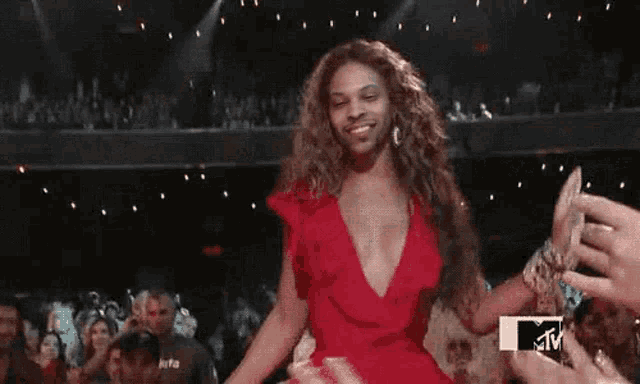 a woman in a red dress is dancing in front of a crowd .