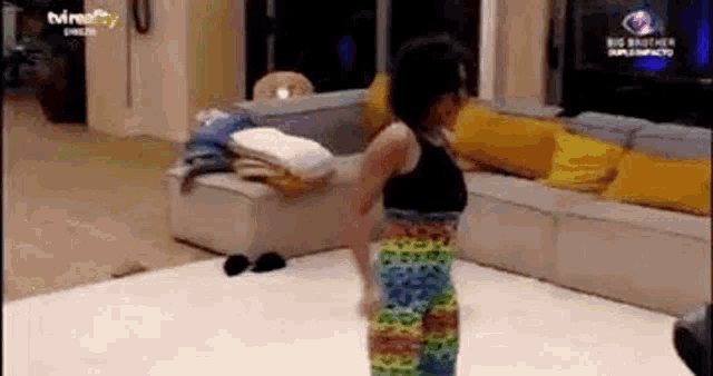 a woman in a colorful dress is dancing in a living room with a couch .
