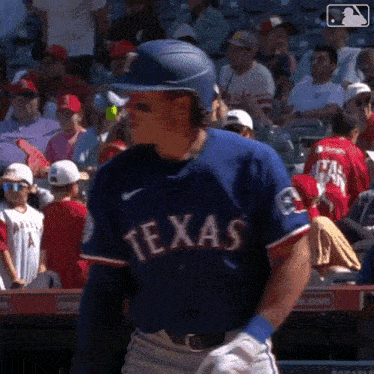 a baseball player for the texas rangers is standing in front of a crowd