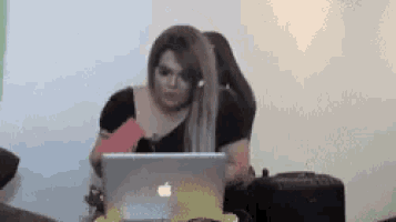 a woman is sitting at a table using an apple laptop .