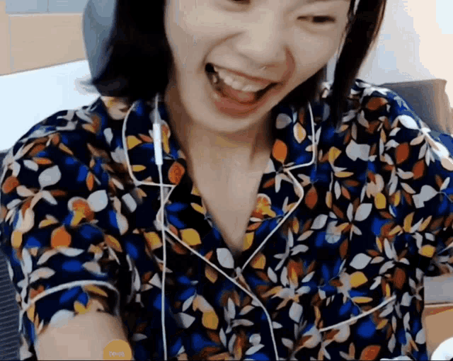 a woman wearing headphones and a floral shirt laughs