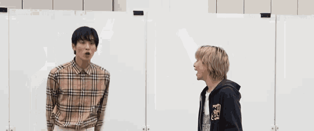 a man wearing a burberry shirt is standing next to another man wearing a black hoodie