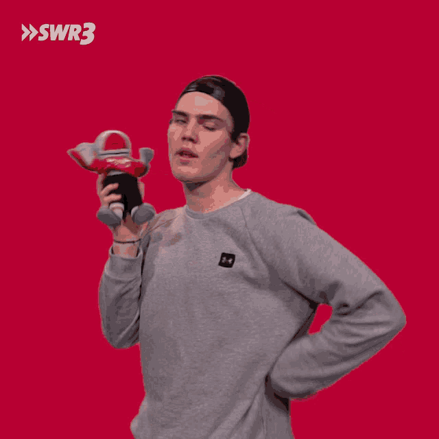 a man holding a stuffed animal in front of a red background with the letters swr3