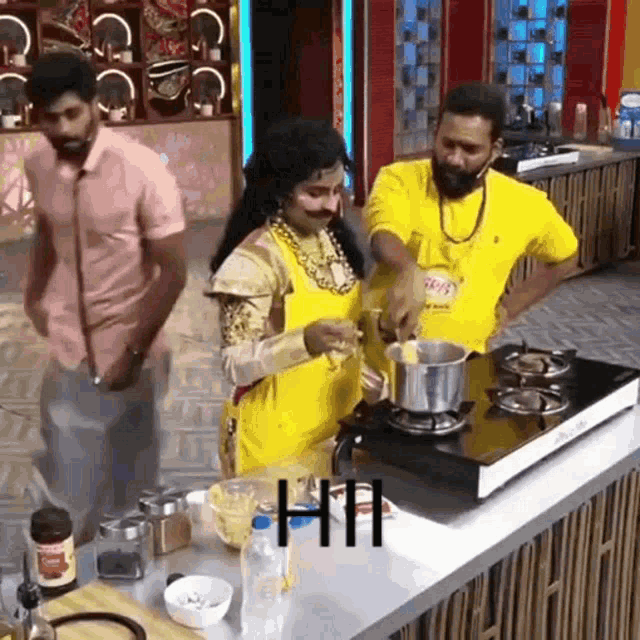 a woman in a yellow apron is cooking on a stove while a man stands behind her .