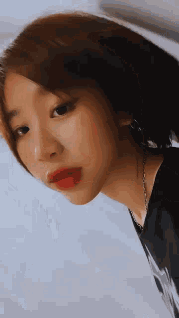 a close up of a woman 's face with red lips and a chain around her neck