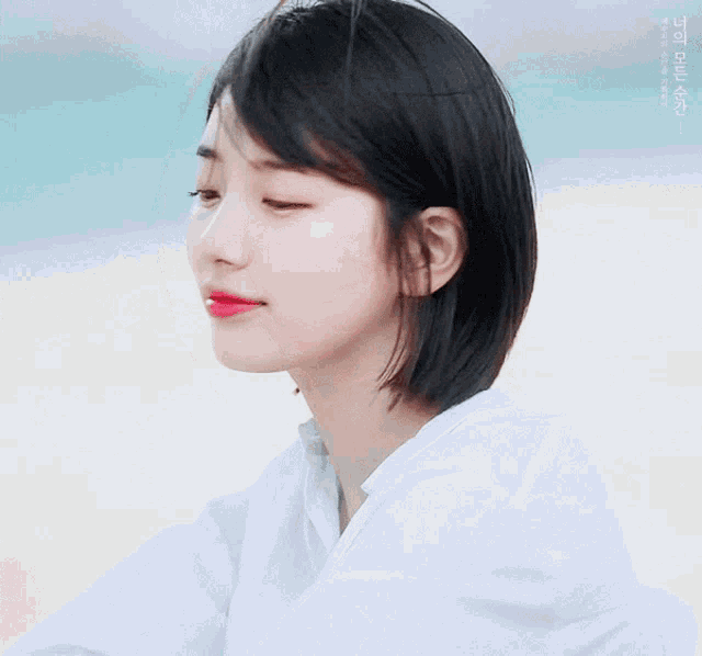 a close up of a woman 's face with her eyes closed and a white shirt on