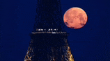 a full moon rises over the eiffel tower