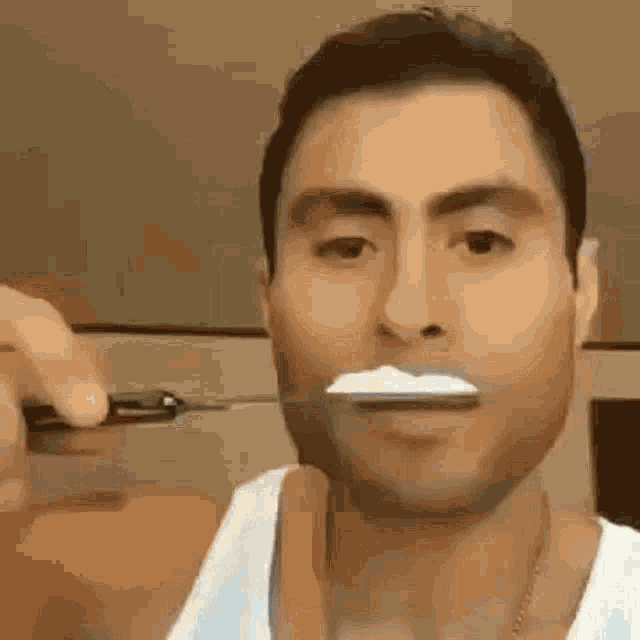a man is brushing his teeth with a knife and toothpaste .