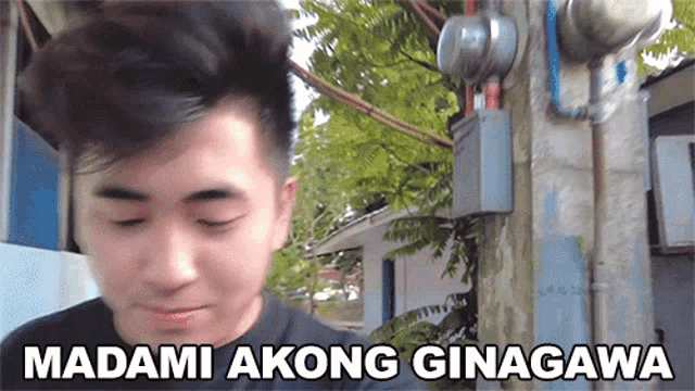 a man is standing in front of a telephone pole with the words " madami akong ginagawa " written on it