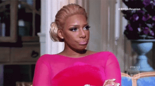a woman in a pink dress is sitting on a couch in a living room .