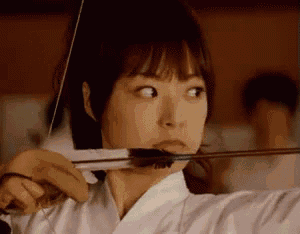 a close up of a woman holding a bow and arrow
