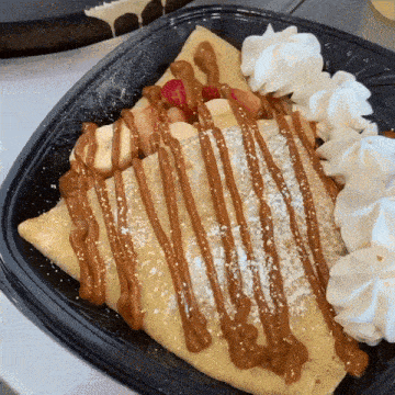a crepe with whipped cream and caramel sauce on top