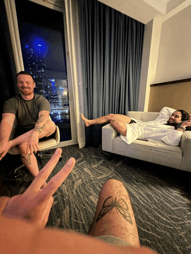 a man with a tattoo on his leg is sitting next to another man