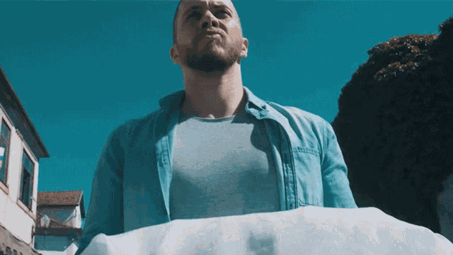 a man in a blue shirt is carrying a white cloth