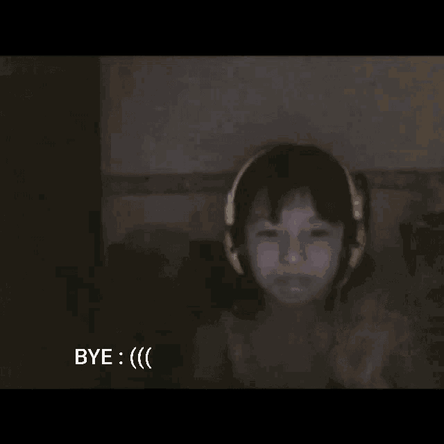 a girl wearing headphones says " bye " in a dark room