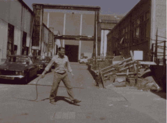 a man in a white shirt is standing on a sidewalk in front of a building that says ' bmw ' on it