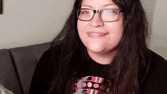 a woman wearing glasses and a black shirt with a pattern on it