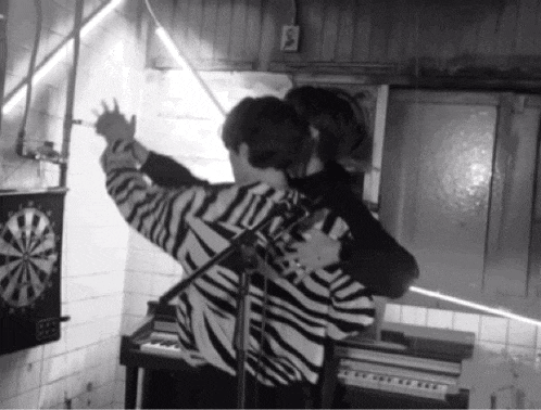 a man wearing a zebra print sweater is hugging another man