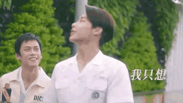 two young men in white uniforms are standing next to each other .