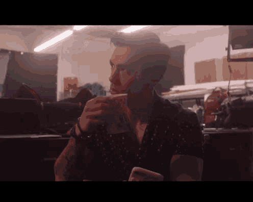 a man is drinking a cup of coffee in a room .
