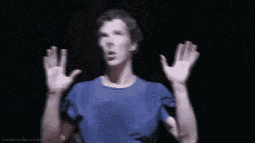 a man in a blue shirt is standing with his arms outstretched .