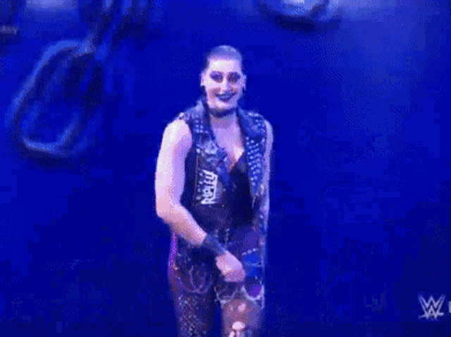 a female wrestler is standing in front of a wall with chains on it