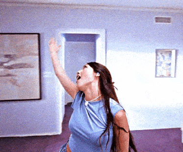 a woman in a blue shirt is dancing in a room with purple carpet