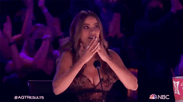 a woman in a sequined dress is sitting in front of a crowd applauding