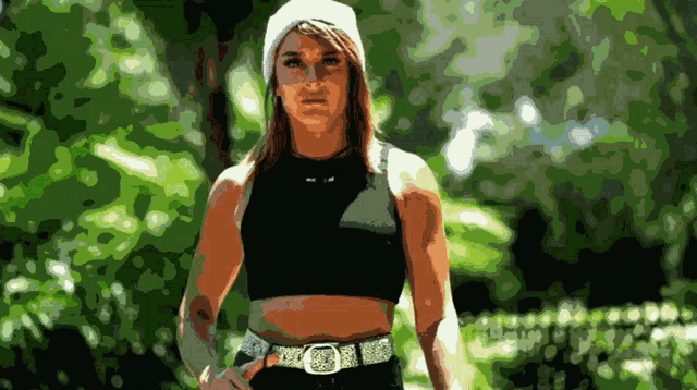 a woman wearing a black top and a white hat is standing in front of trees