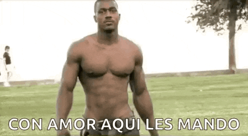 a shirtless man is standing in a park with the words `` con amor aqui les mando '' .