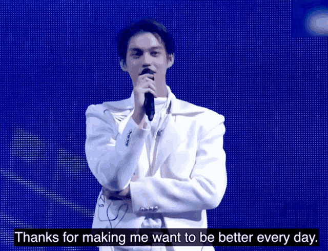 a man in a white suit singing into a microphone with the words thanks for making me want to be better every day below him