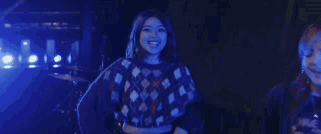 a woman is dancing with her hands in the air in a dark room