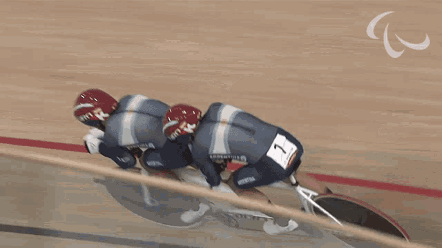 two cyclists wearing giro helmets are riding a tandem bike