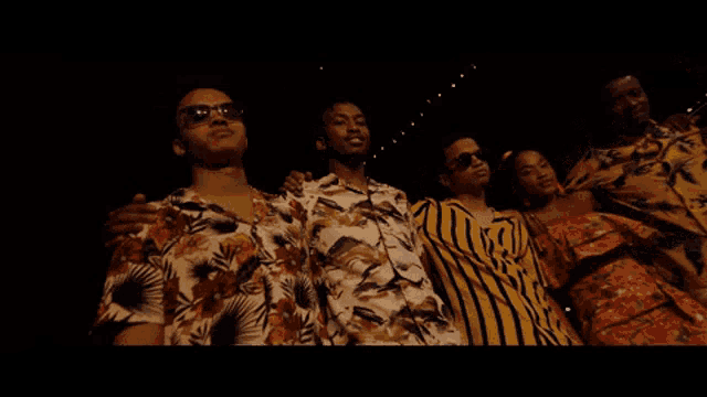 a group of people wearing hawaiian shirts are posing for a photo