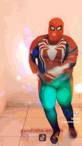 a man in a spiderman costume is dancing in a room .