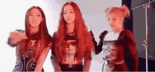 a group of three women with red hair are standing next to each other .