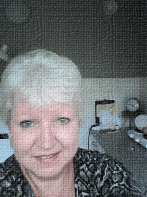 a woman is taking a selfie in front of a clock in a kitchen .