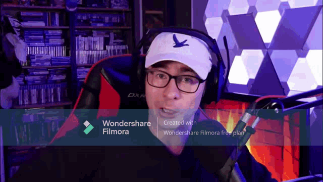 a man wearing headphones and a hat is sitting in front of a screen that says wondershare filmora on it