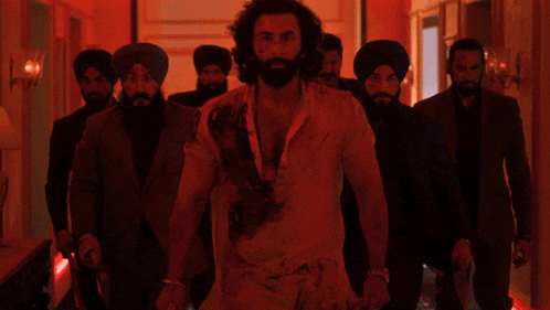 a man with a beard is surrounded by men in suits