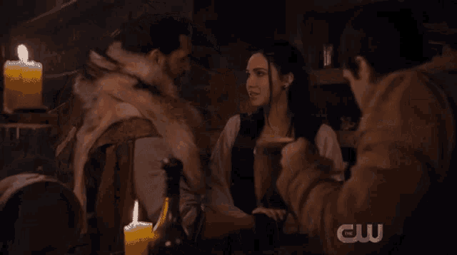 a group of people are sitting at a table with candles and a cw logo in the corner