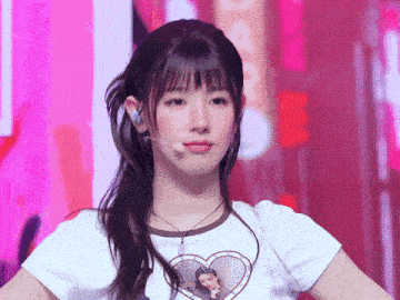 a girl wearing a white shirt with a heart on it looks at the camera