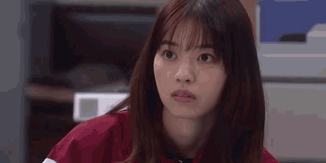 a young woman in a red jacket is making a funny face and looking at the camera .