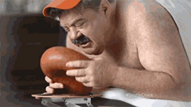 a shirtless man with a mustache is holding a basketball in his hands .