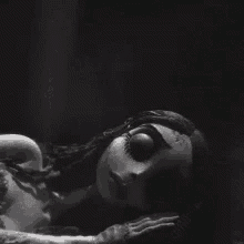 a black and white photo of a doll laying on the ground