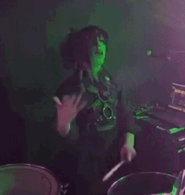 a woman is playing drums in front of a microphone in a dark room .