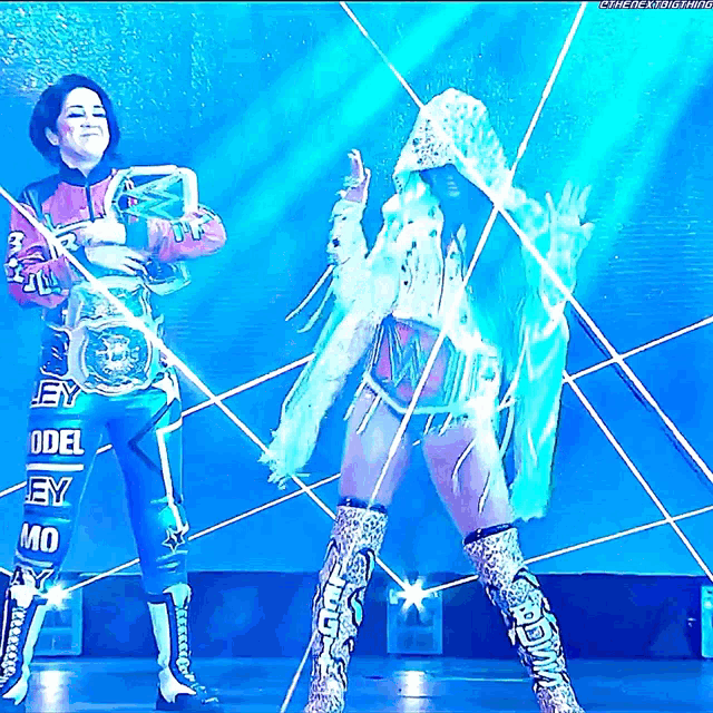 two women are dancing on a stage and one of them has a belt that says odel ey on it