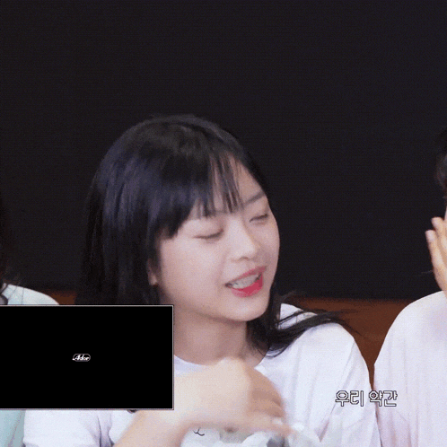 a girl is holding a stuffed bunny with a blue eye and a black screen behind her that says aeee