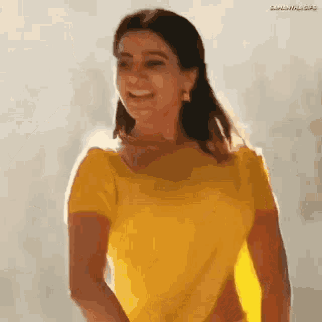 a woman in a yellow shirt is smiling and looking to the side .