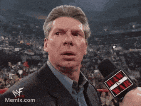 a man in a suit is talking into a microphone with a wwe logo on it