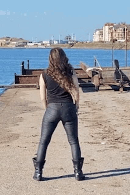 a woman in leather pants is standing on a beach